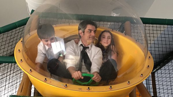 John, with his children Anna and Lucas in some sort of McDonald's Play Place bubble. John wears a shirt and tie and probably shouldn't be in there.